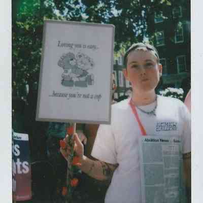 A person holds a sign reading, "Loving you is easy... because you're not a cop".