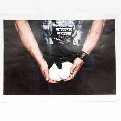 Photo shows lower body of figure in black T shirt & leather wristband holding plaster cast at hip/groin height.
