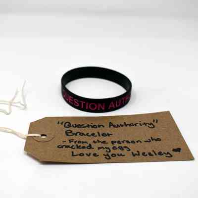 The image shows a "Question Authority" bracelet and tag with a personal message from Wesley.