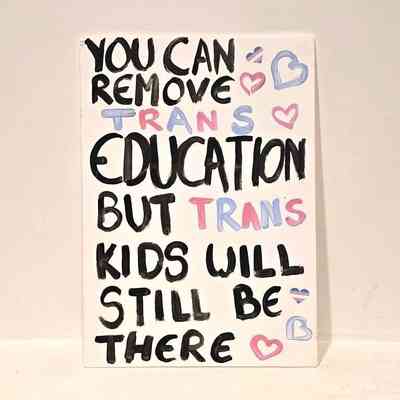 A placard which is white with black writing that says 'I'm not trapped in my body I'm trapped in other peoples perceptions of my body'.