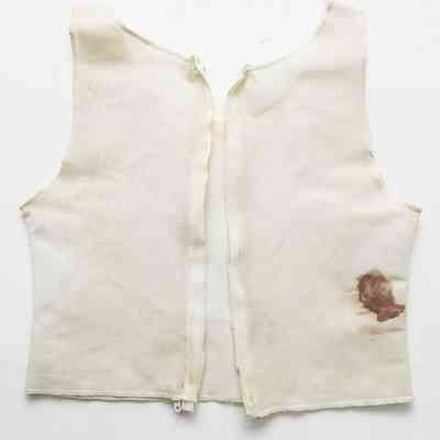 A plain white vest-style binder with a prominent brown stain is laid out flat on a white background.