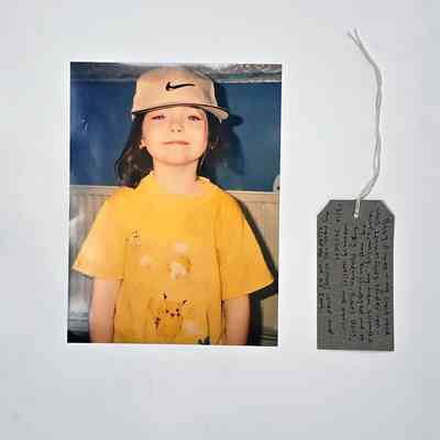 A photo of a child wearing a Nike baseball cap and a yellow Pokemon t-shirt. With a brown handwritten luggage tag.