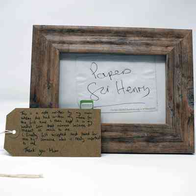 A wooden frame displays a handwritten note, accompanied by a heartfelt message on a tag.