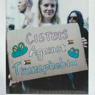 A person is holding a cardboard sign reading "Cisters Against Transphobia".