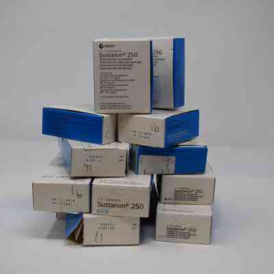 A stack of boxes labeled "Sustanon 250" is arranged, featuring blue and white packaging.