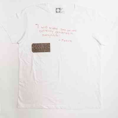 A white T-shirt features a quote in red handwriting and a small handwritten cardboard tag.