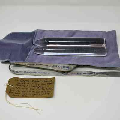 Two clear perspex dilators on a purple cloth bag, with a Soul Source ribbon and a brown, handwritten luggage tag.