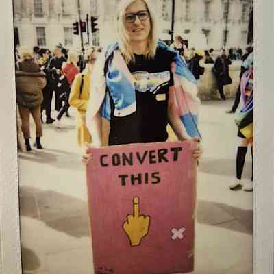 A person holding a sign that says “CONVERT THIS” with a middle finger gesture.