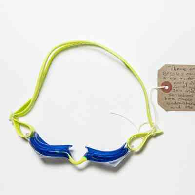 A pair of goggles with a lime green band, navy blue rims, and clear lenses.