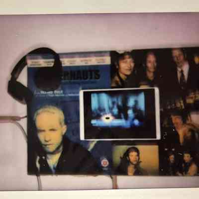 A small display features headphones, posters, photographs, and a tablet with a blurred screen.