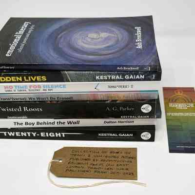 A stack of books with diverse themes is accompanied by a bookmark and handwritten note.