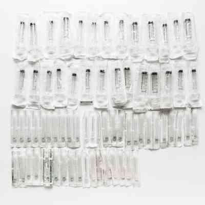 Rows of sterican plastic syringes on a white background.