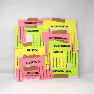 The image shows colorful city names on paper with tape, including London and Manchester.