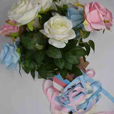 A bouquet of flowers which are fake roses in trans flag colours, tied up with the same coloured ribbons.