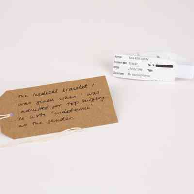 A white hospital medical bracelet. With a brown, handwritten luggage tag.