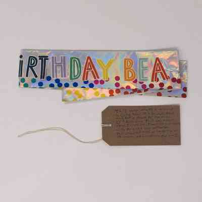 A silver birthday banner which is colourful and says 'Birthday'.
