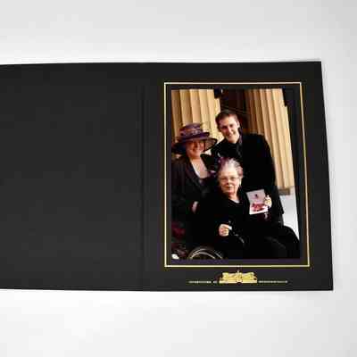 A group of three people pose together, with one holding a certificate in a framed photograph.