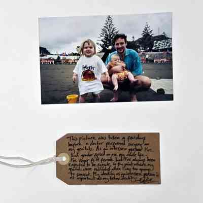 Colour photograph; group picture taken outdoors of adult male holding baby with a toddler in Tweenies T shirt.