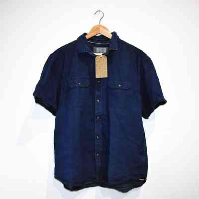 A blue short-sleeved shirt hangs on a wooden hanger against a plain white background.