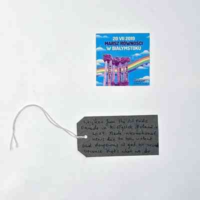 A square sticker which has a blue background and a rainbow and clouds. There is text on it.