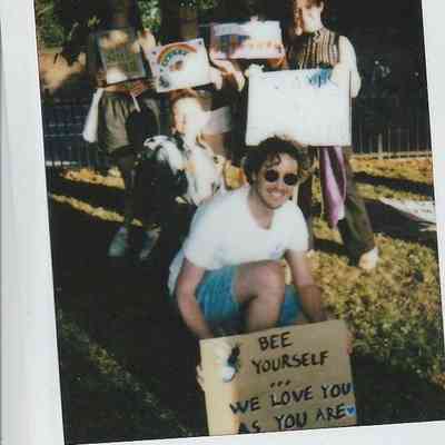 A group of people are holding supportive signs outdoors, promoting acceptance and love for everyone.