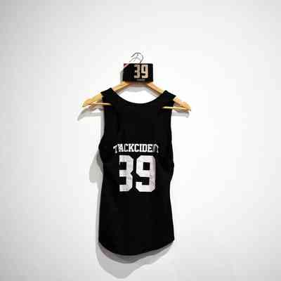 A black tank top with "TRACKCIDENT 39" hangs on a wooden hanger.