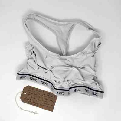 A homemade binder made from a tank top is displayed with visible safety pins and a note.