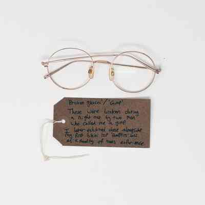 A pair of broken glasses lies above a handwritten note, recounting their damaging incident.