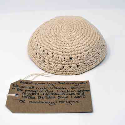 A beige crocheted kippah sits near a handwritten note discussing nonbinary and religious identity.