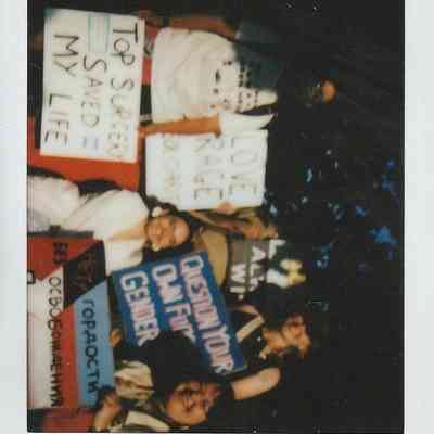 A group of people holds various protest signs promoting body autonomy and gender choice.