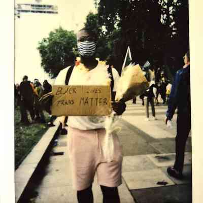 A person holds a "Black Trans Lives Matter" sign.