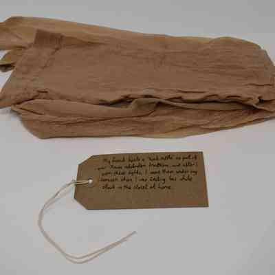 Pair of beige/natural tights with a brown handwritten luggage tag.