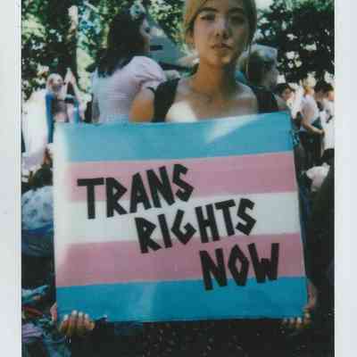 A person holds a "Trans Rights Now" sign at London Trans Pride in Soho, 2022.