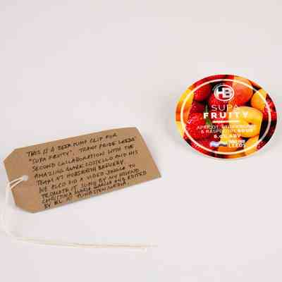 A beer pump clip for "Supa Fruity", brewed by Horsforth Brewery. The background shows apricots, strawberries and raspberries. With a brown, handwritten luggage tag.