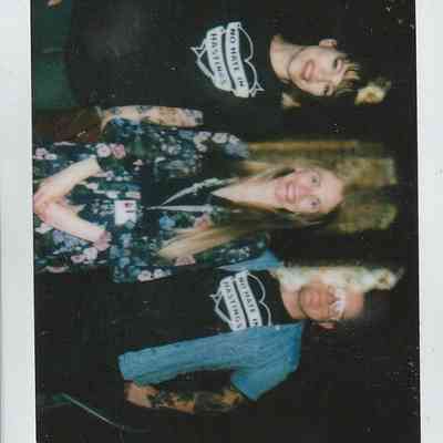 Three people are smiling in a group photo at Hastings Museum during an event in 2023.