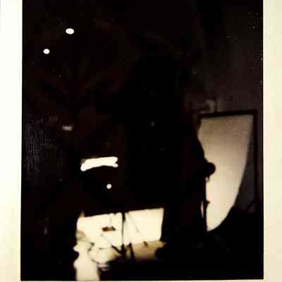 A dark lit polaroid which vaguely shows a photography lighting set up.
