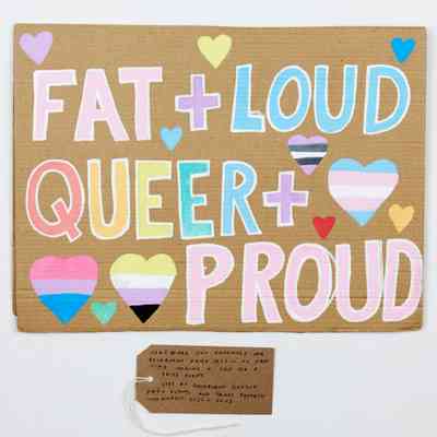 A placard which says Fat and loud, queer and proud in pastel colourful colours.