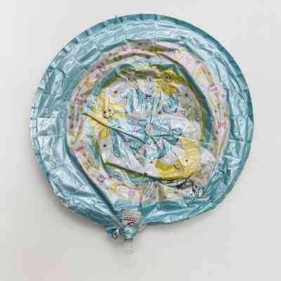 The image shows a deflated foil balloon with text “It's a Boy” designed with stars and alphabet