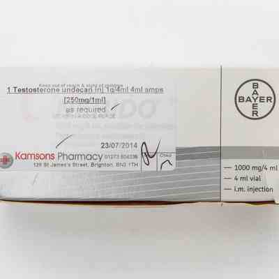 Box for "Nebido" testosterone ampoules sitting on a wooden surface. There is a faded label for Kamsons Pharmacy stuck to the top.