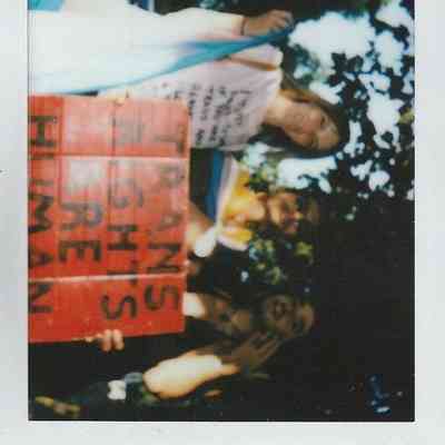 The image shows people holding a sign reading "Trans Rights are Human Rights." They are outdoors.