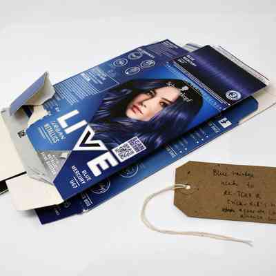 Two empty, flattened boxes of Schwartzkopf Urban Metallics Blue Mercury hair die. With a brown, handwritten luggage tag.