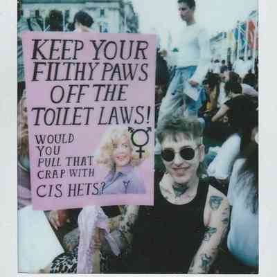 A person holding a placard which says "Keep Your Filthy Paws Off The Toilet Laws".