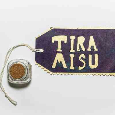 A  glass jar with cork next to a label which says TIRA MISU.