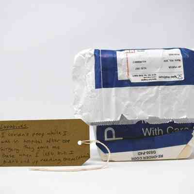 A blue and white paper prescription bag, containing laxatives. With a brown, handwritten luggage tag.