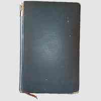          Front Cover; The image shows an old, hardbound book with a dark green cover that has visible signs of wear, including small scratches and scuffs across its surface, and a slightly frayed spine at the top and bottom, indicating its age and extensive use over time; a small piece of brown ribbon protrudes from the bottom of the book, serving as a bookmark, adding a touch of vintage charm to its overall appearance, while the book rests against a plain, light gray background, allowing its details to stand
   