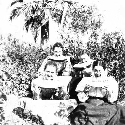 Ellerhorst sisters (Mariotti) 8 inches: Photograph of four of the five Ellerhorst sisters eating watermelon outside among bushes and trees.