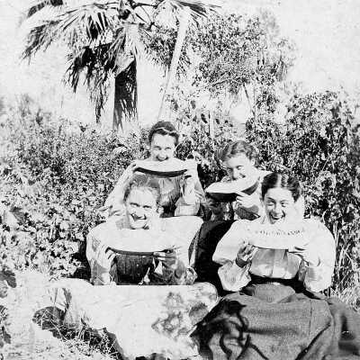 Ellerhorst sisters (Mariotti): Photograph of four of the five Ellerhorst sisters eating watermelon outside among bushes and trees.