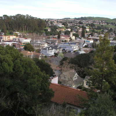 P1010046**: A 1970s photo taken from approximately the same location shows a grove of eucalyptus trees protecting the site of the beloved Pinole-Hercules School #1, which was demolished in 1968, and a modern downtown with a thriving business district.