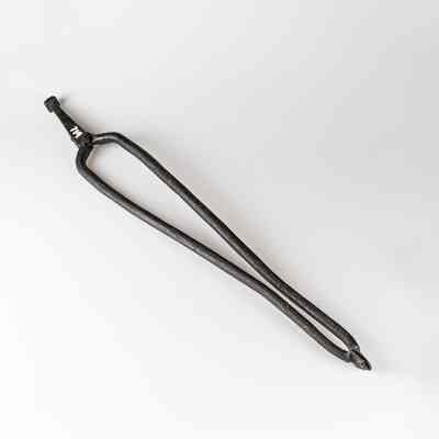 A pair of vintage, rusty, large tongs is placed against a white background. / Une paire de grandes pinces vintage rouillées est posée sur un fond blanc.