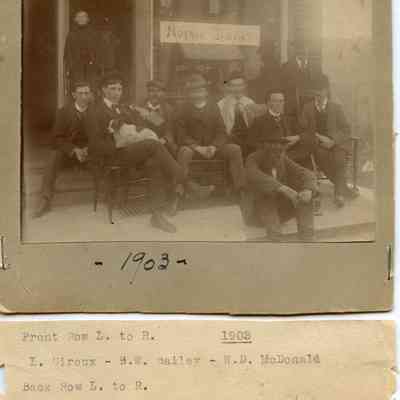 Group of Men Seated in Front of Store